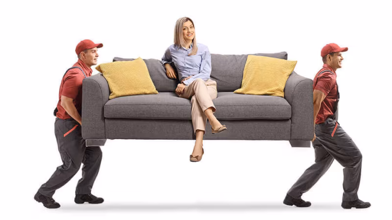 Two movers carrying a sofa with a woman sitting on it