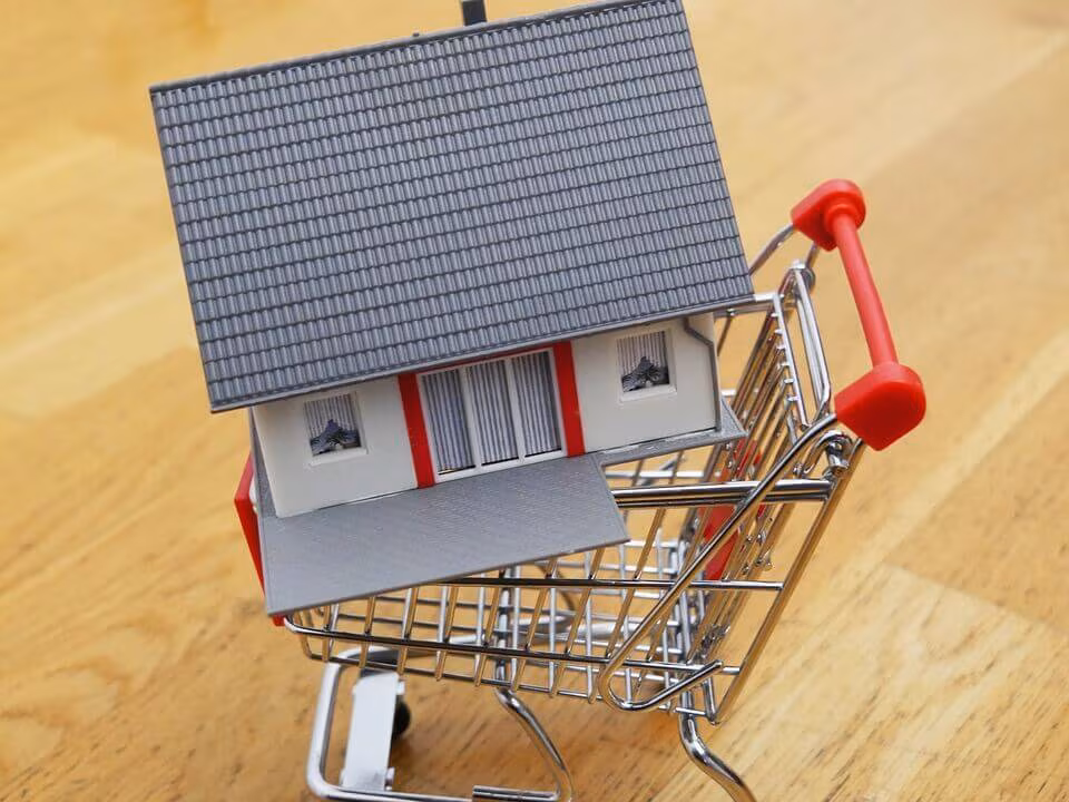 A model house sitting in a miniature shopping trolley