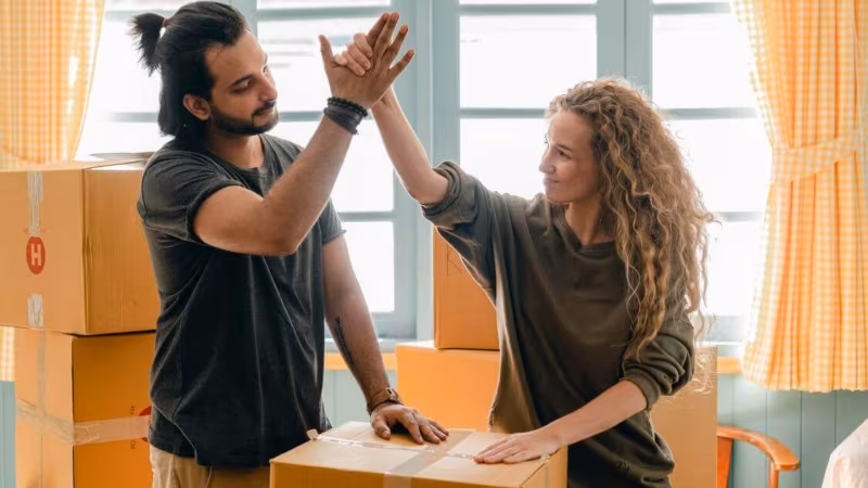 A couple high-fiving over a cardboard box
