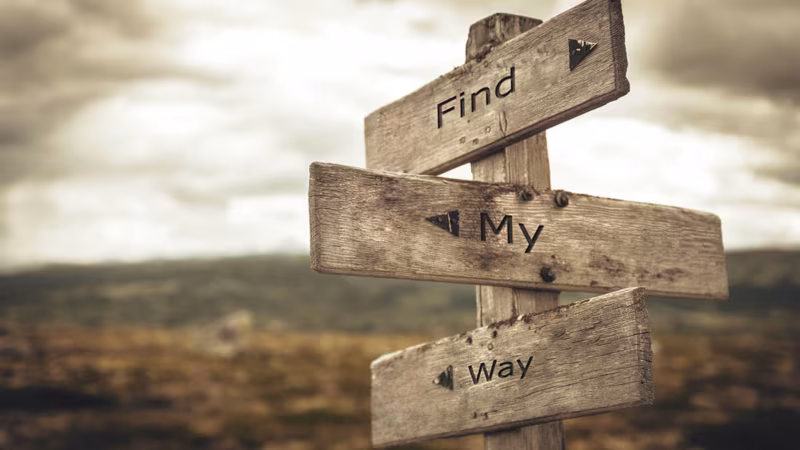 A wooden signpost reading Find my way against a cloudy sky