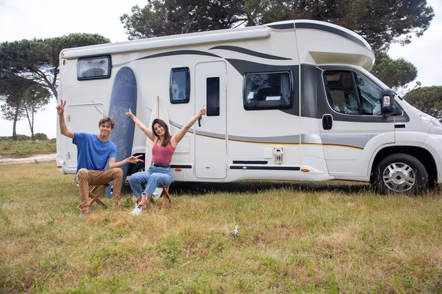 Couple sitting in front of their trailer after cross-country moving