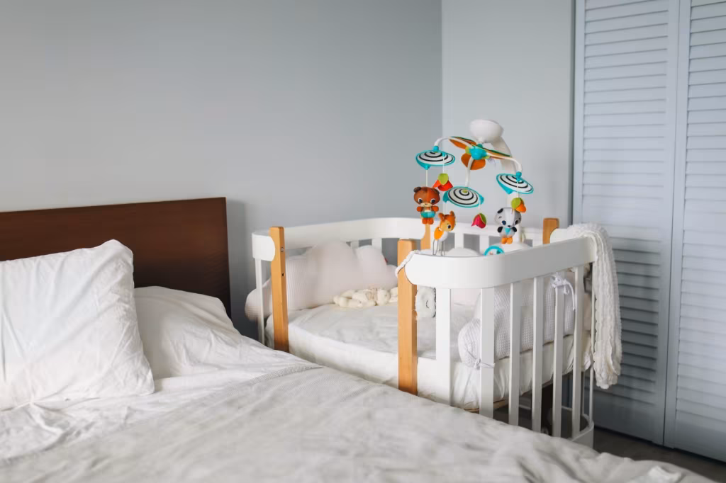 A crib next to the bedroom bed
