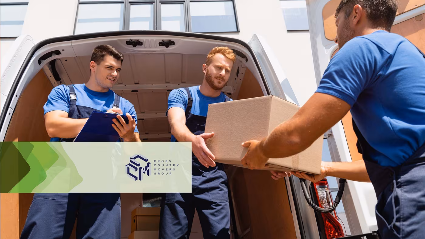 Three movers passing cardboard boxes at the back of a van