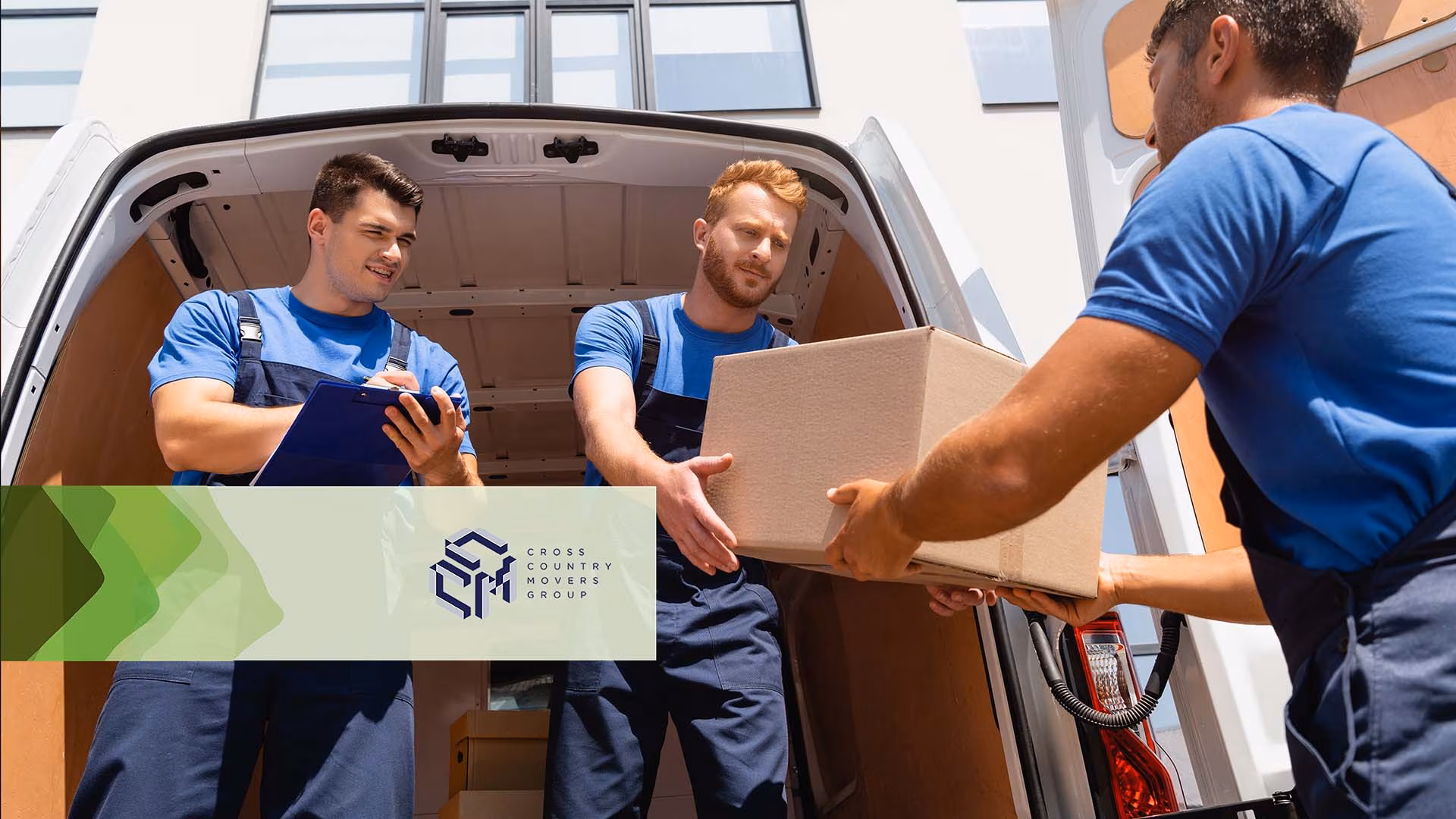 Three movers passing cardboard boxes at the back of a van