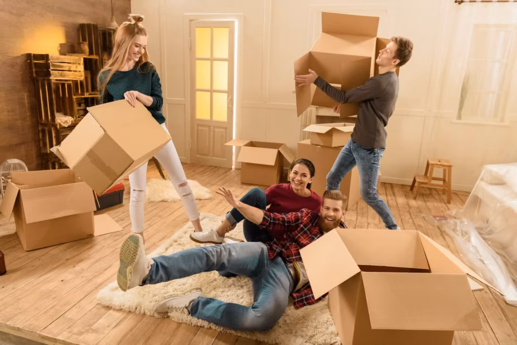 Happy people carrying empty moving boxes into their new home after relocation