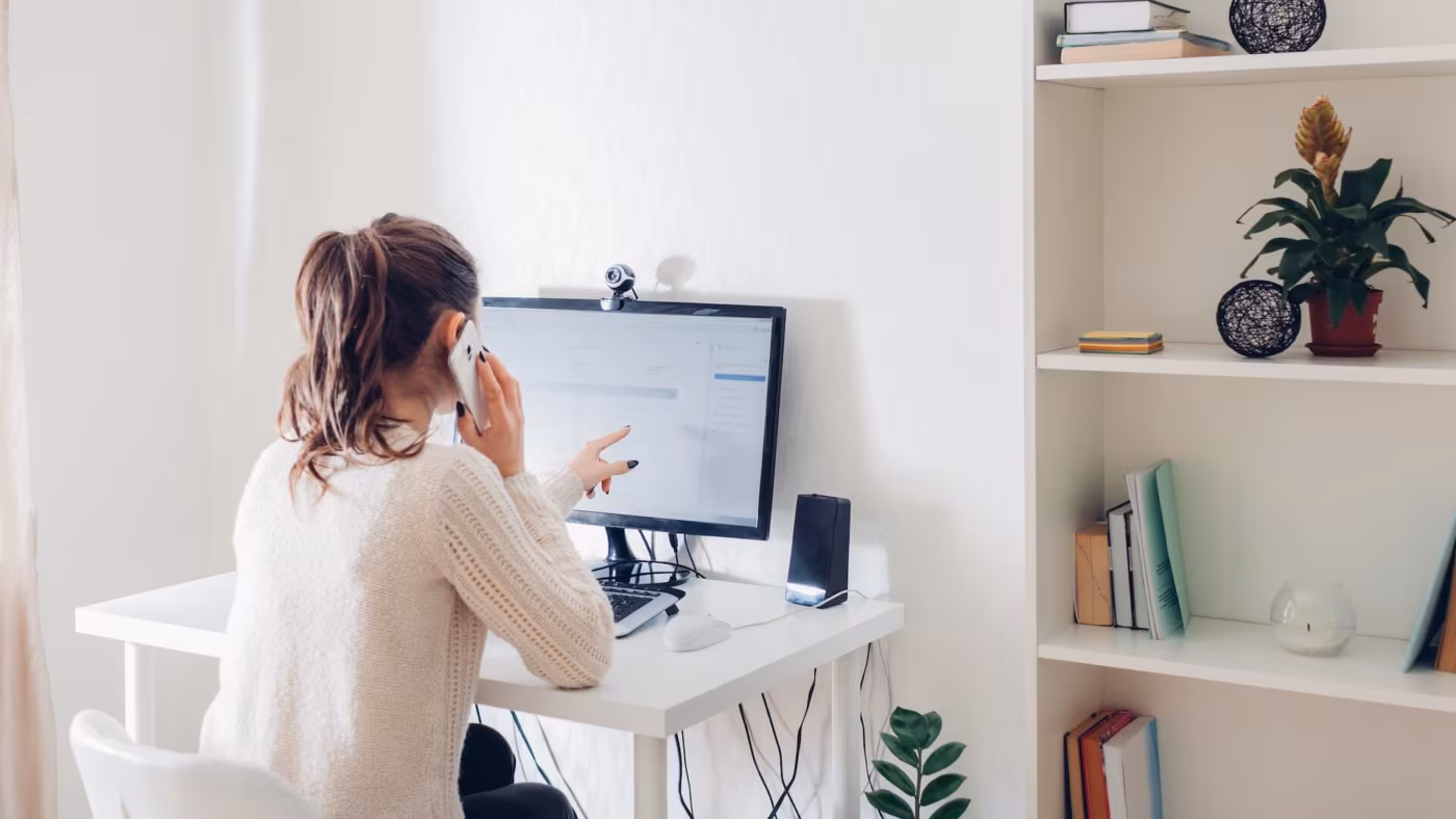 A woman talking on the phone in front of a computer