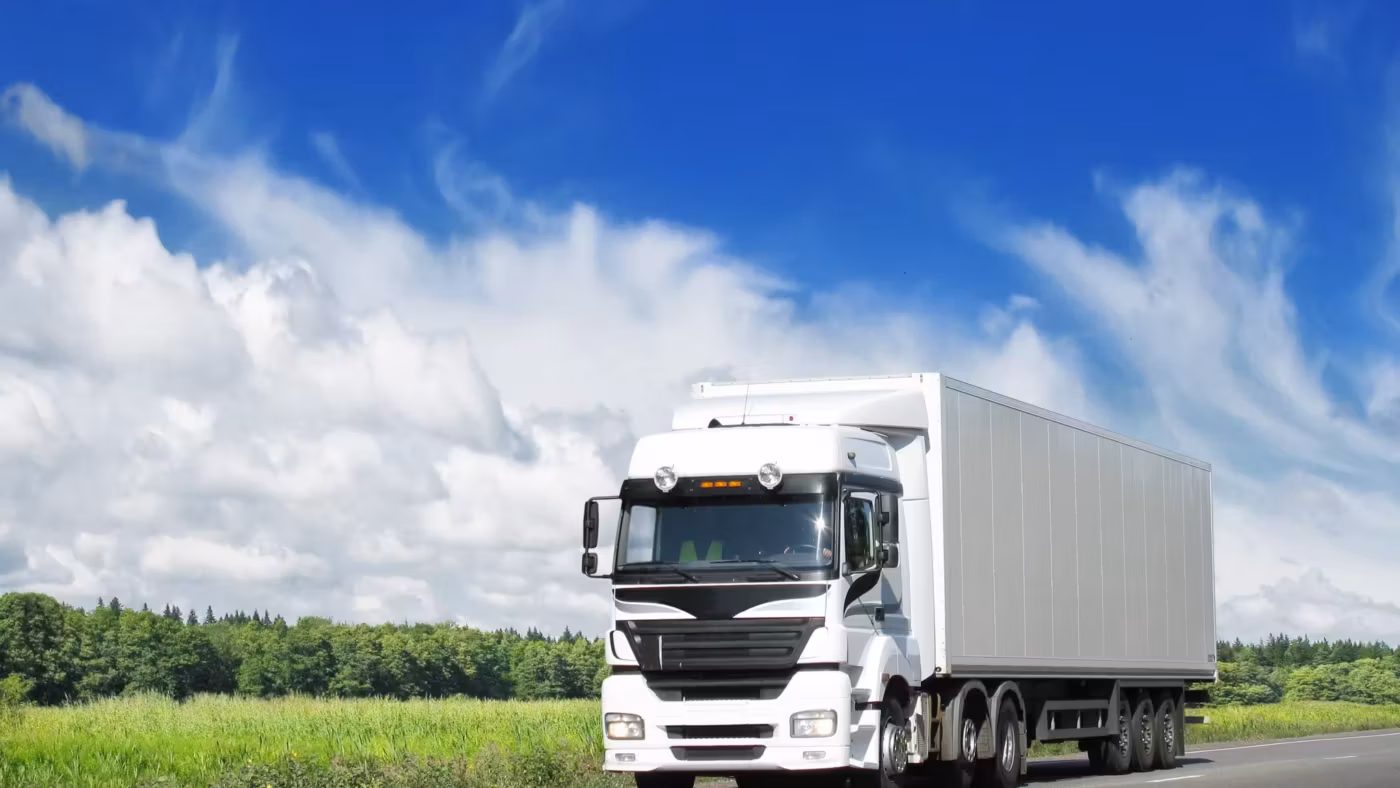A truck with a plain box trailer on an open road under a wide sky