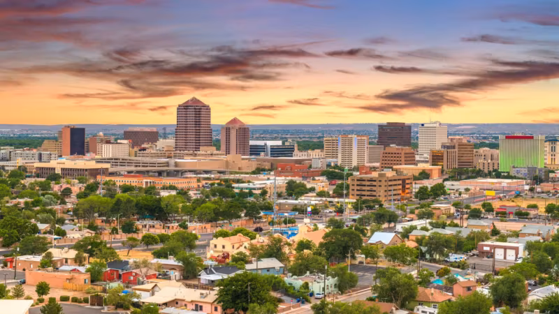 Downtown Albuquerque at sunset with low adobe-colored houses in the foreground