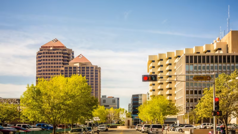 A downtown Albuquerque street with the Albuquerque Plaza tower above the trees