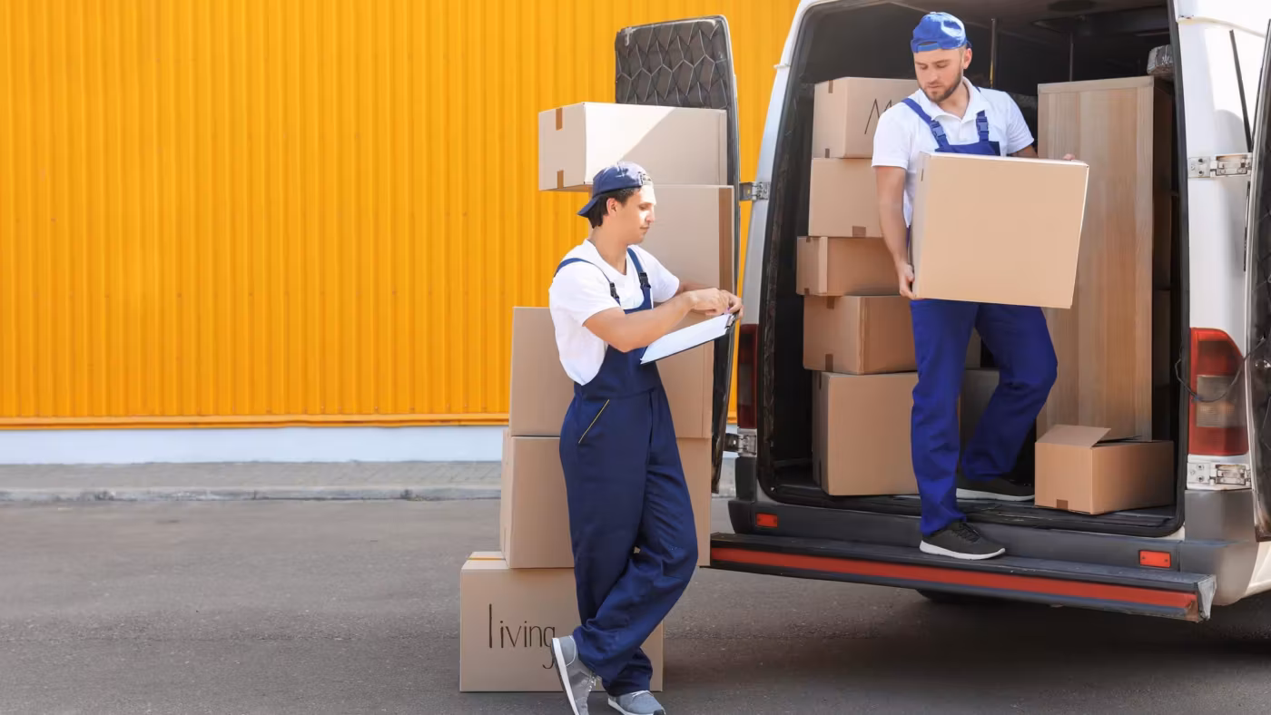 A mover loading cartons into a van backed up to a roller shutter