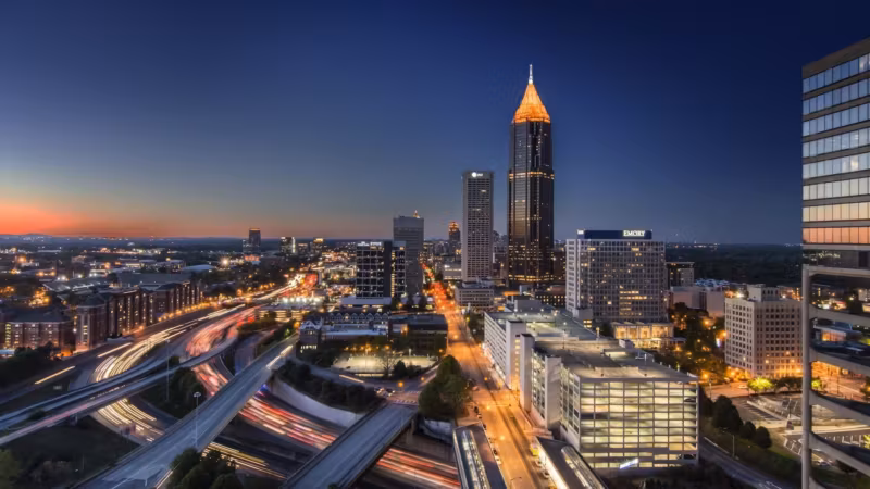 Downtown Atlanta at dusk with traffic light trails on the freeway below