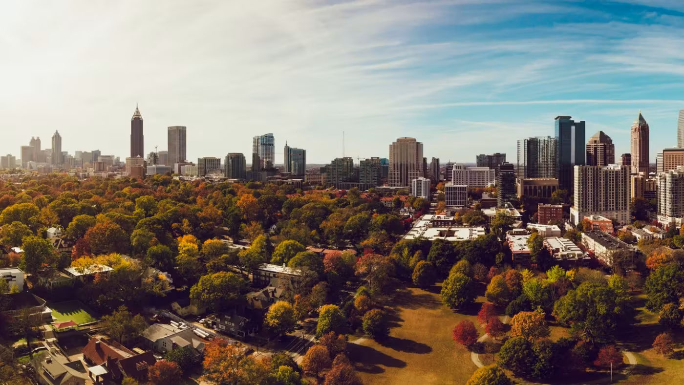 Atlanta's skyline beyond a dense canopy of trees turning in autumn