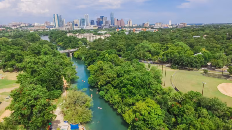 A green creek in the Austin greenbelt with the downtown towers in the distance