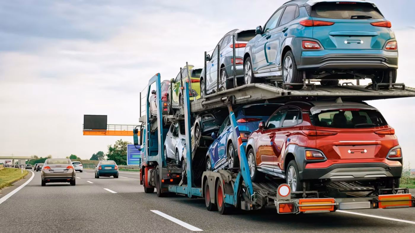 A full-length car carrier in profile on a highway, loaded on both decks
