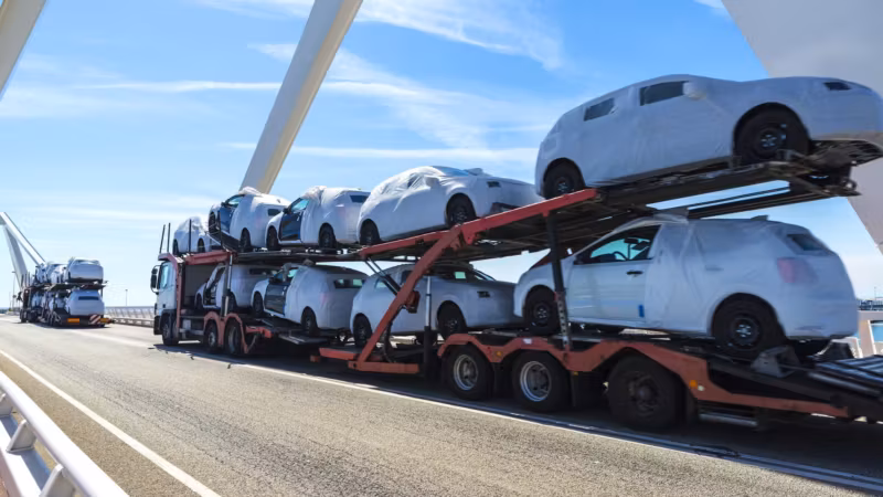 A loaded car carrier on a highway, vehicles stacked on its upper and lower decks