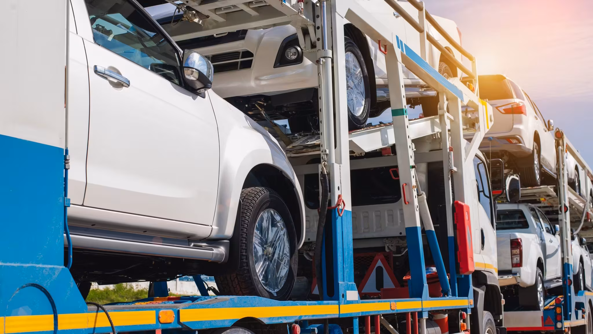 A white pickup loaded high on the upper rack of a car carrier