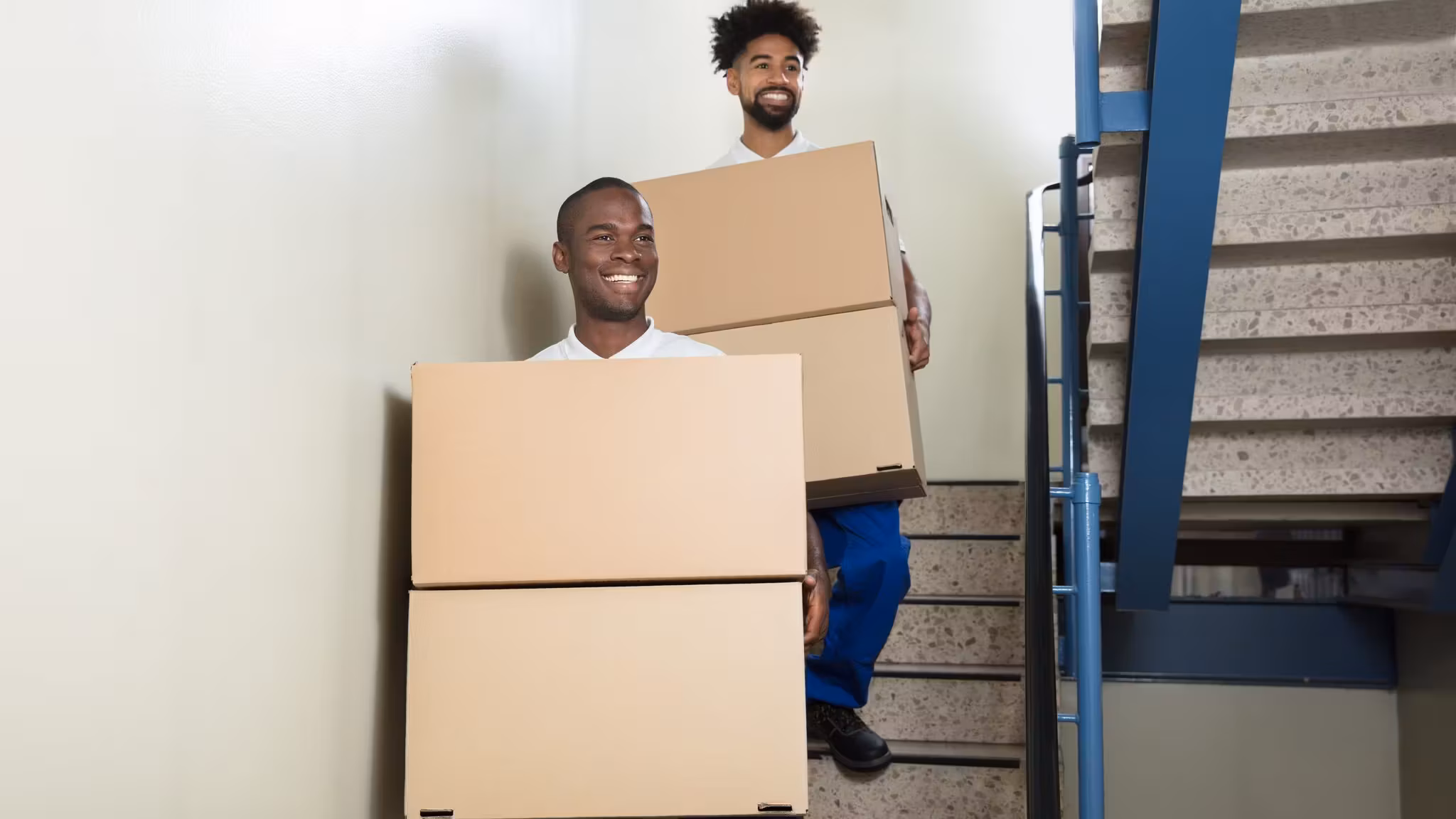 A mover carrying a carton down a flight of stairs