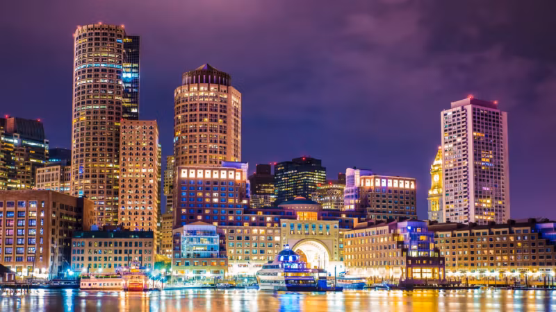 Boston Harbour at night with the downtown towers lit and reflected in the water