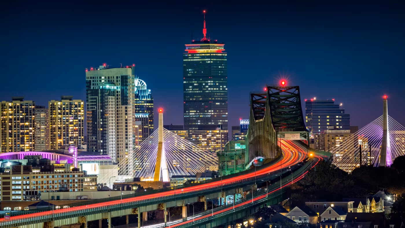 The Zakim Bridge and elevated highway into Boston, traffic drawn out in light trails at dusk