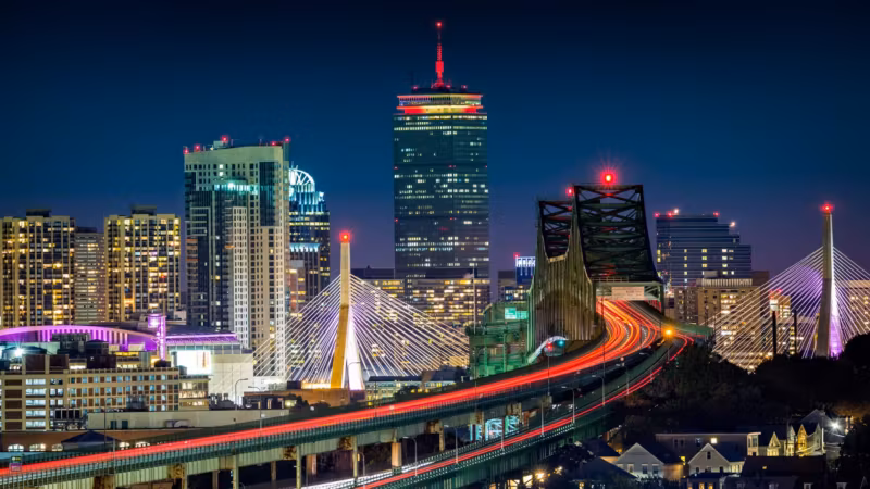 The Zakim Bridge and elevated highway into Boston, traffic drawn out in light trails at dusk