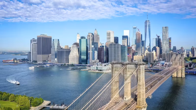 The Brooklyn Bridge from above with the park on the Brooklyn shore and Lower Manhattan beyond