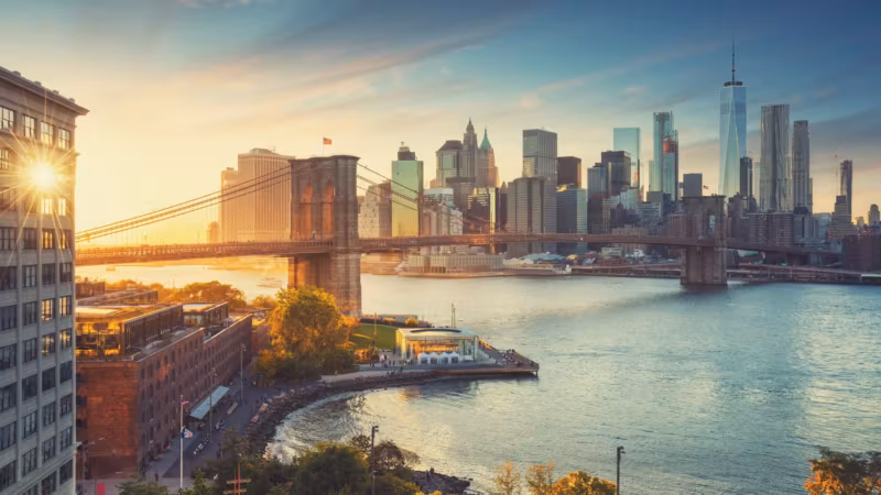 The Brooklyn waterfront at sunrise with the Brooklyn Bridge and Lower Manhattan across the East River