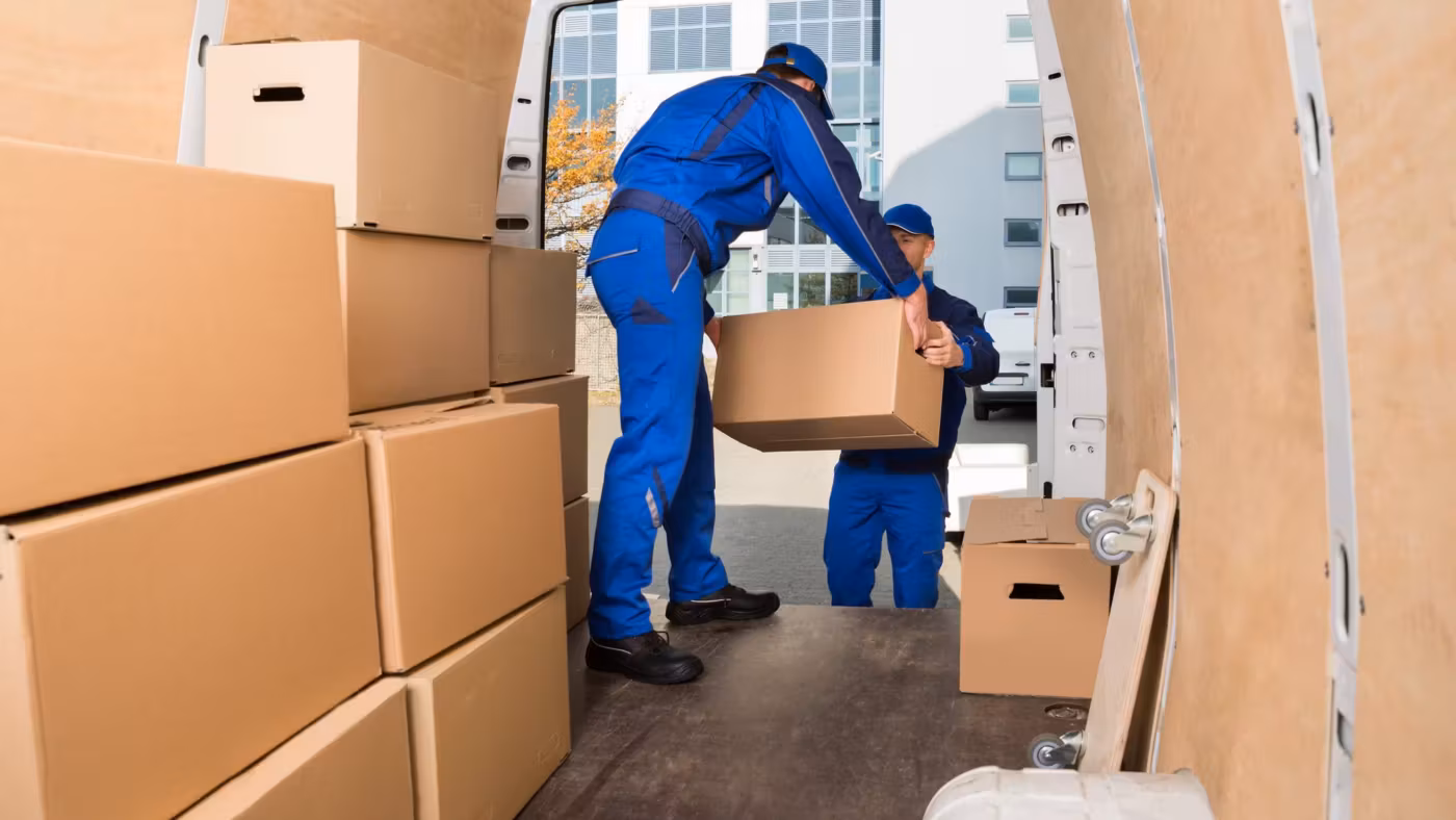 A mover loading cartons into a van already stacked to the roof