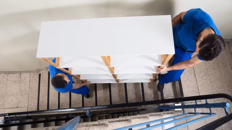 A mover guiding a large panel past a stair rail