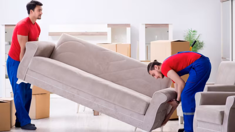 A mover tipping a sofa on its end to clear a doorway