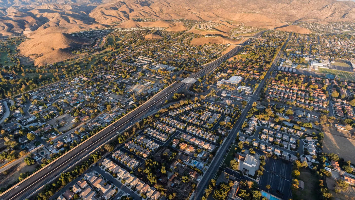 Aerial view of a California town spread along a freeway below dry hills