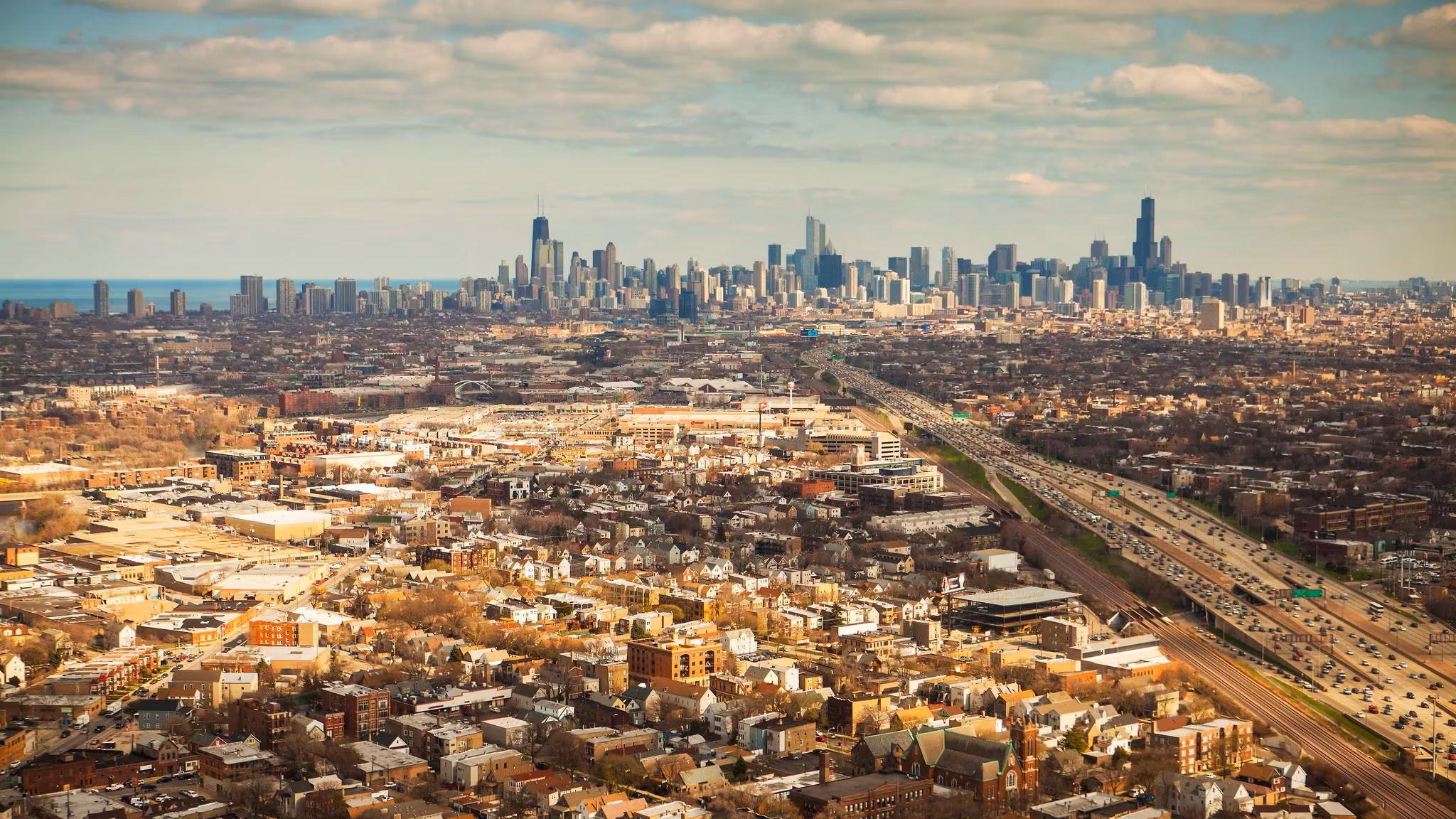 Aerial view over Chicago's low-rise neighborhoods with the downtown skyline beyond