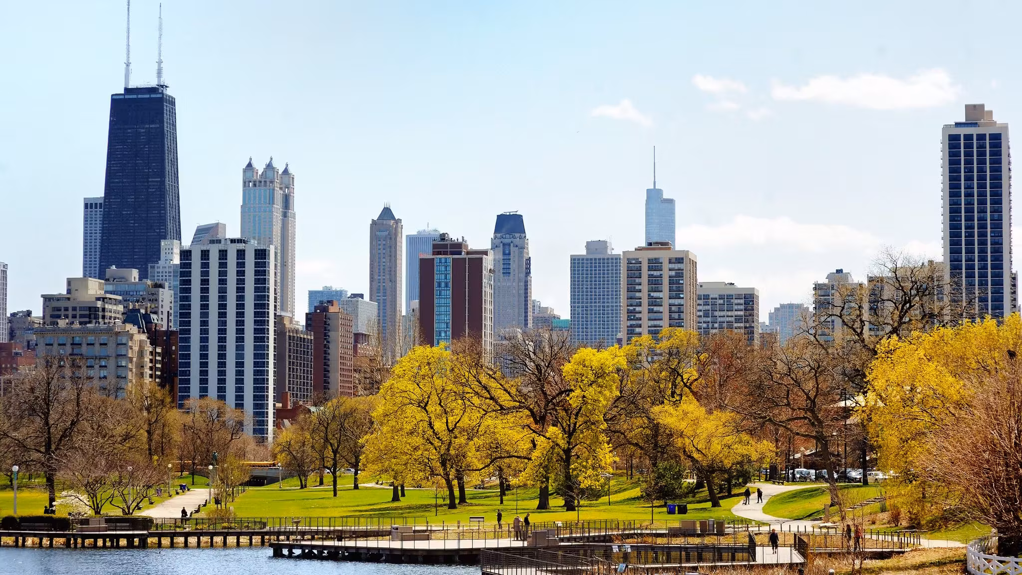 The Chicago skyline above a lakefront park and a wooden pier in spring
