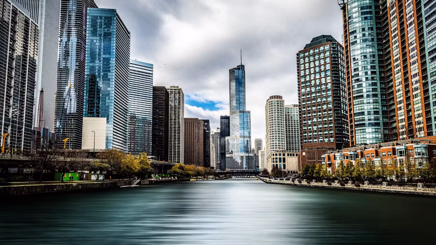 The Chicago River running between glass towers under a broken sky