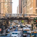 Traffic on a Chicago street with an elevated train crossing overhead