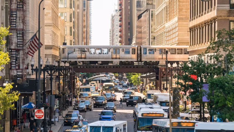 Traffic on a Chicago street with an elevated train crossing overhead