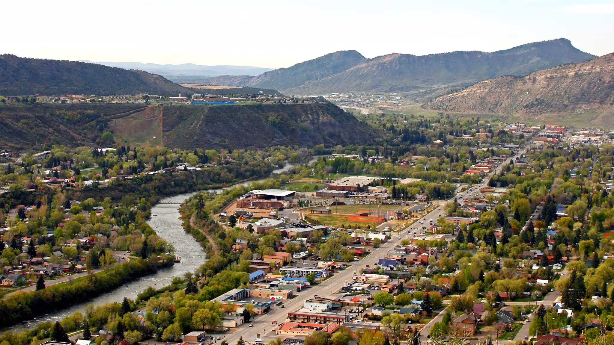 A Colorado town spread along a river valley below a flat-topped mesa
