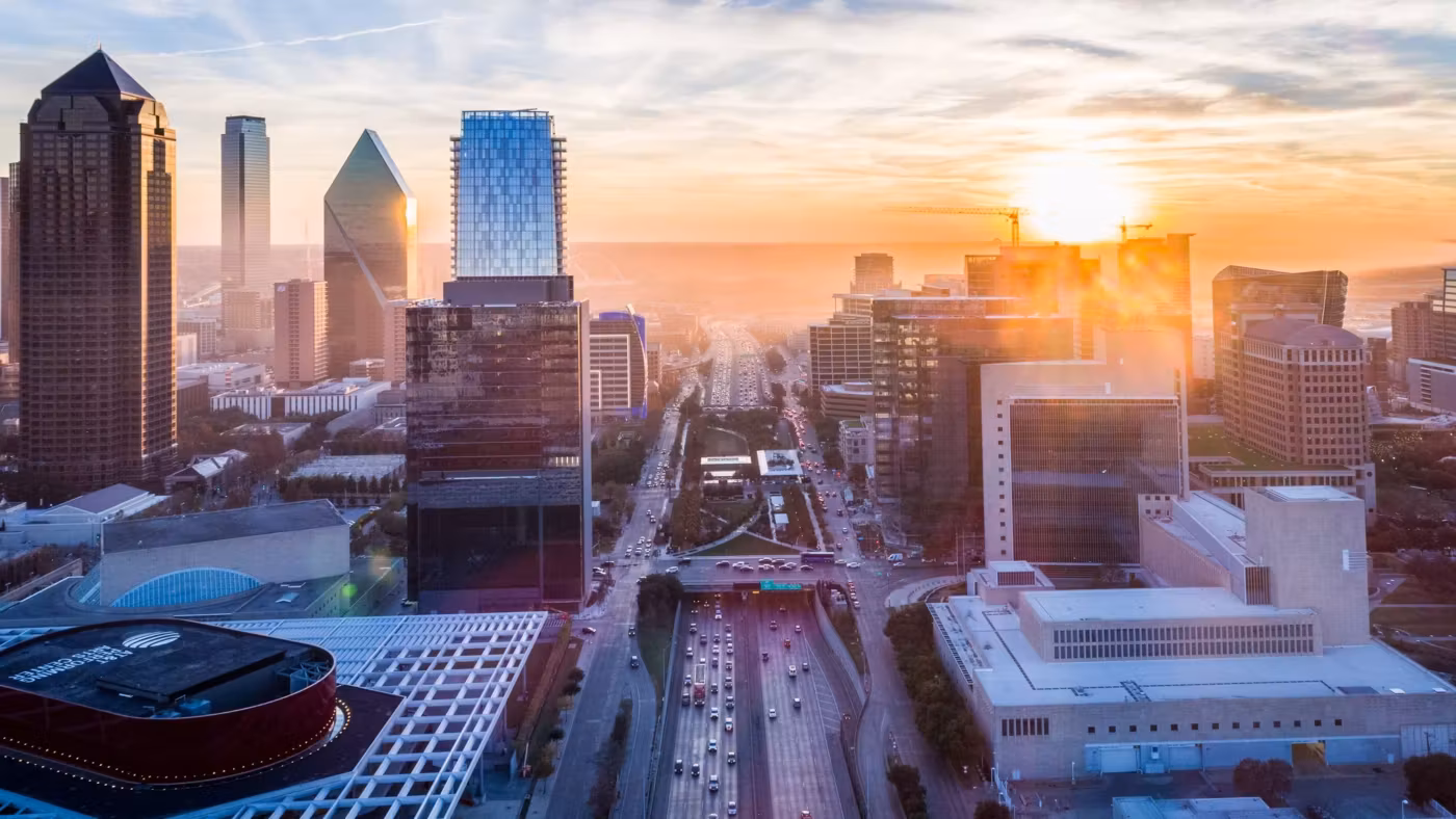 Downtown Dallas at sunrise, the sun breaking between the towers