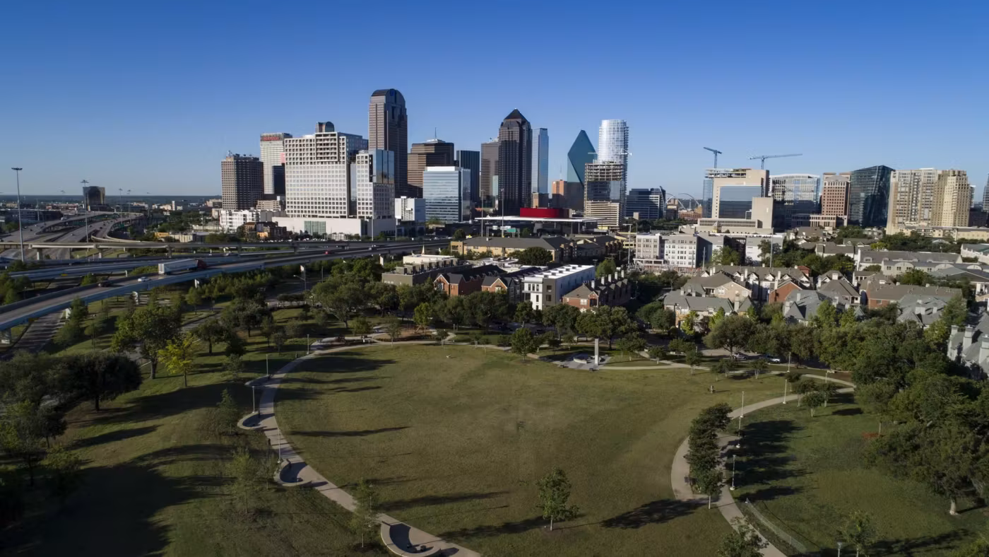 A green park in Dallas with the downtown towers rising behind it