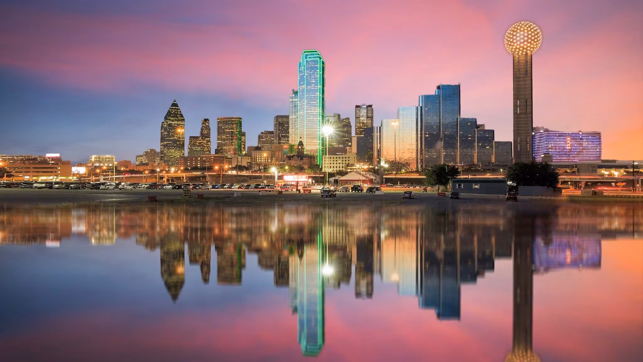 The Dallas skyline reflected in still water at dusk with Reunion Tower at the right