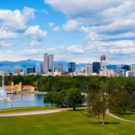 Denver's skyline behind the City Park lake and pavilion, with the Rocky Mountains on the horizon