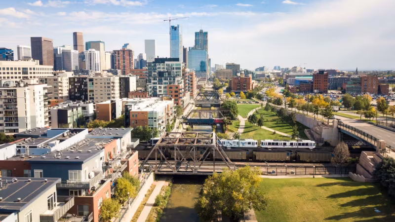 New apartment buildings along the South Platte River in Denver with a light-rail bridge crossing it