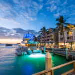 A marina in Florida at dusk with a lit boat moored beside waterfront buildings