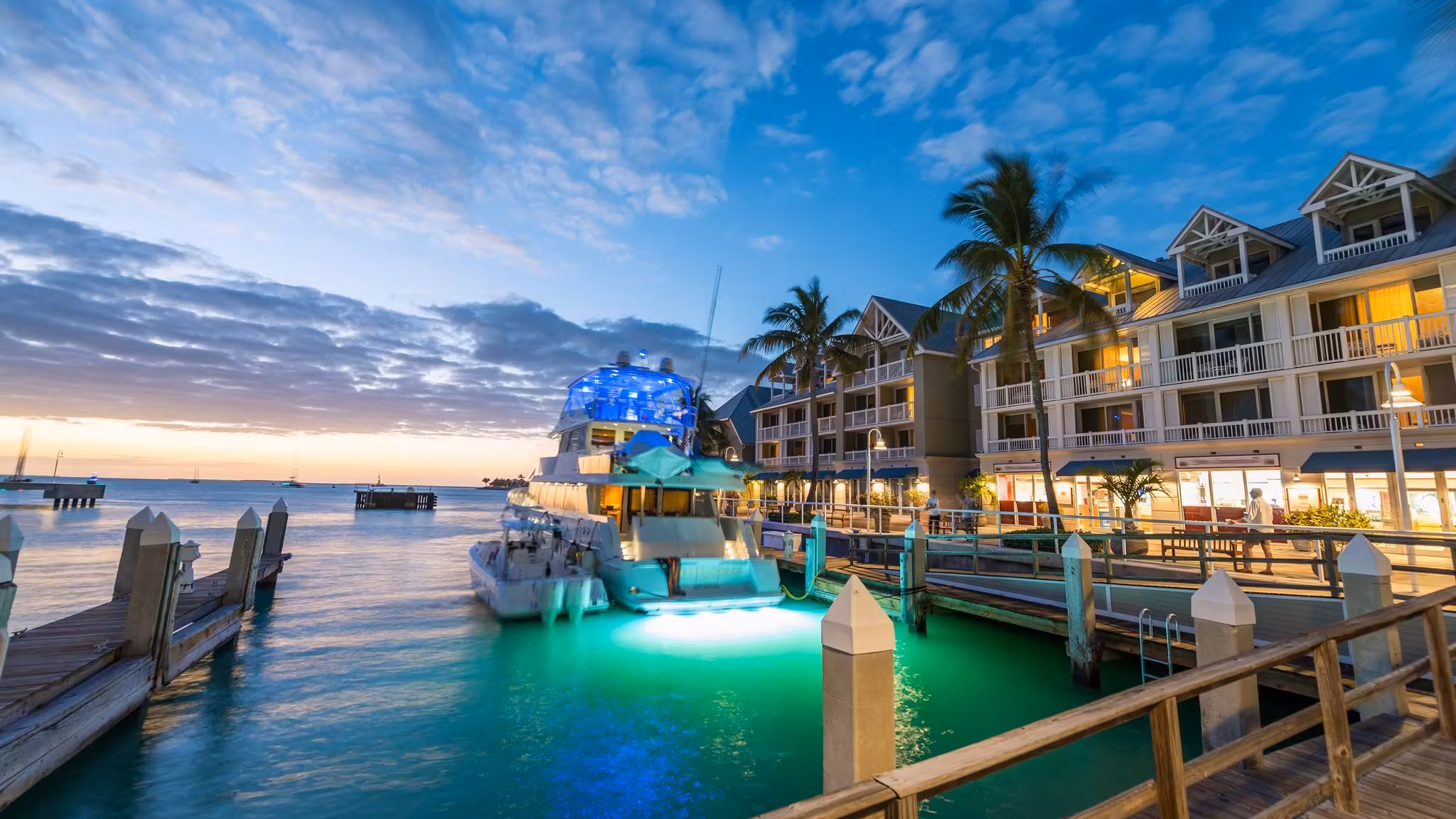 A marina in Florida at dusk with a lit boat moored beside waterfront buildings