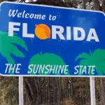 A Welcome to Florida sign among pines beside the road