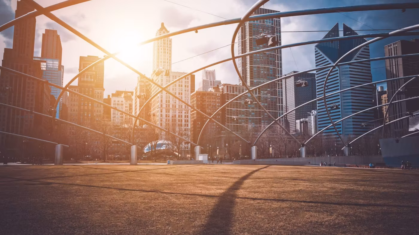 The steel trellis of a Chicago park pavilion with the towers behind