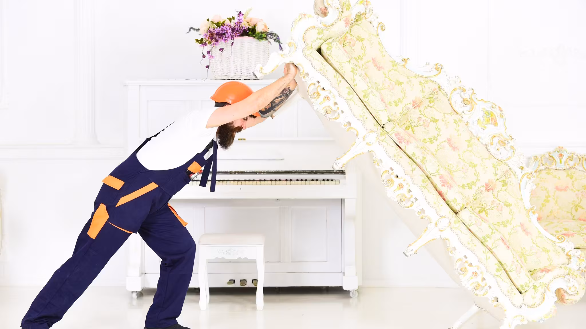 A mover lifting one end of an ornate sofa clear of the floor