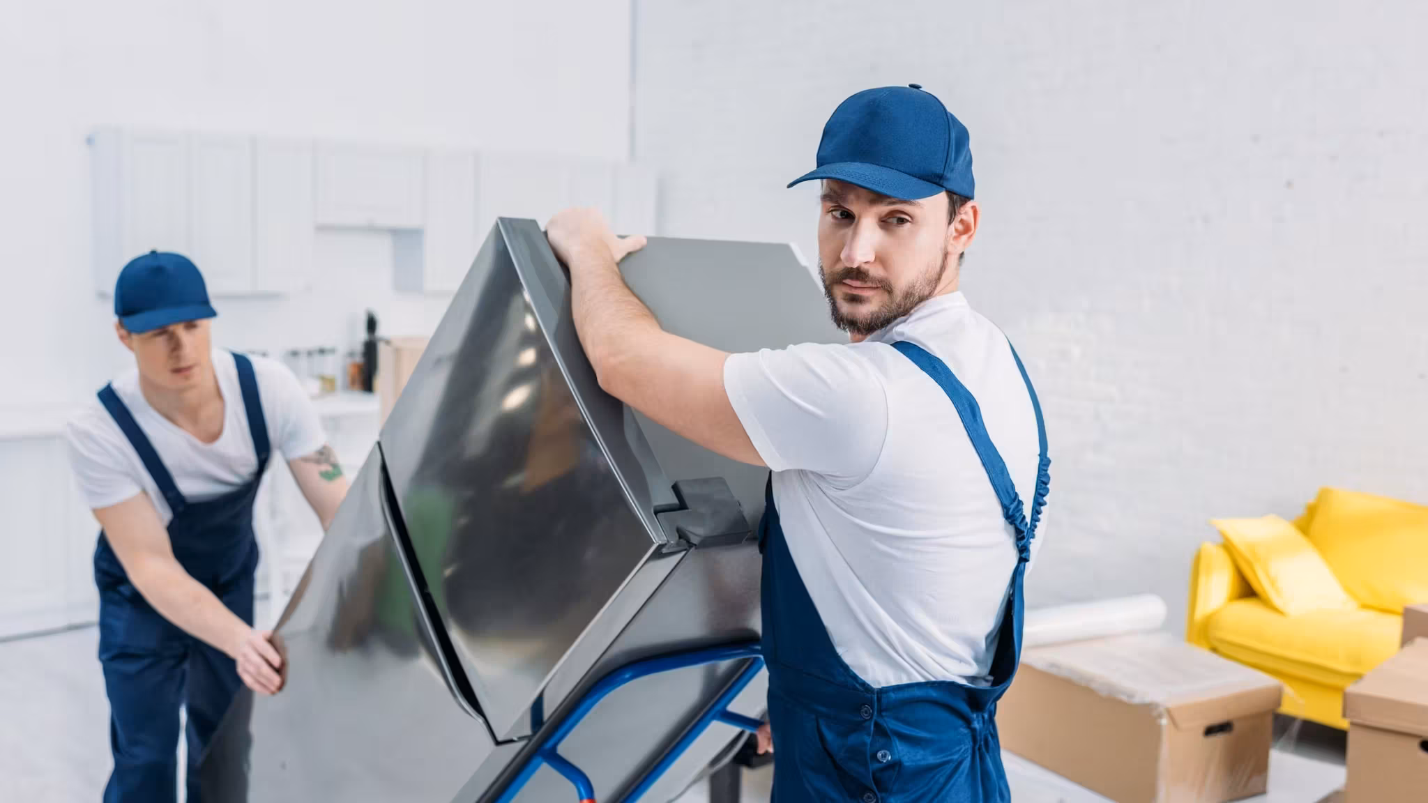Two movers carrying a large flat-screen television between them