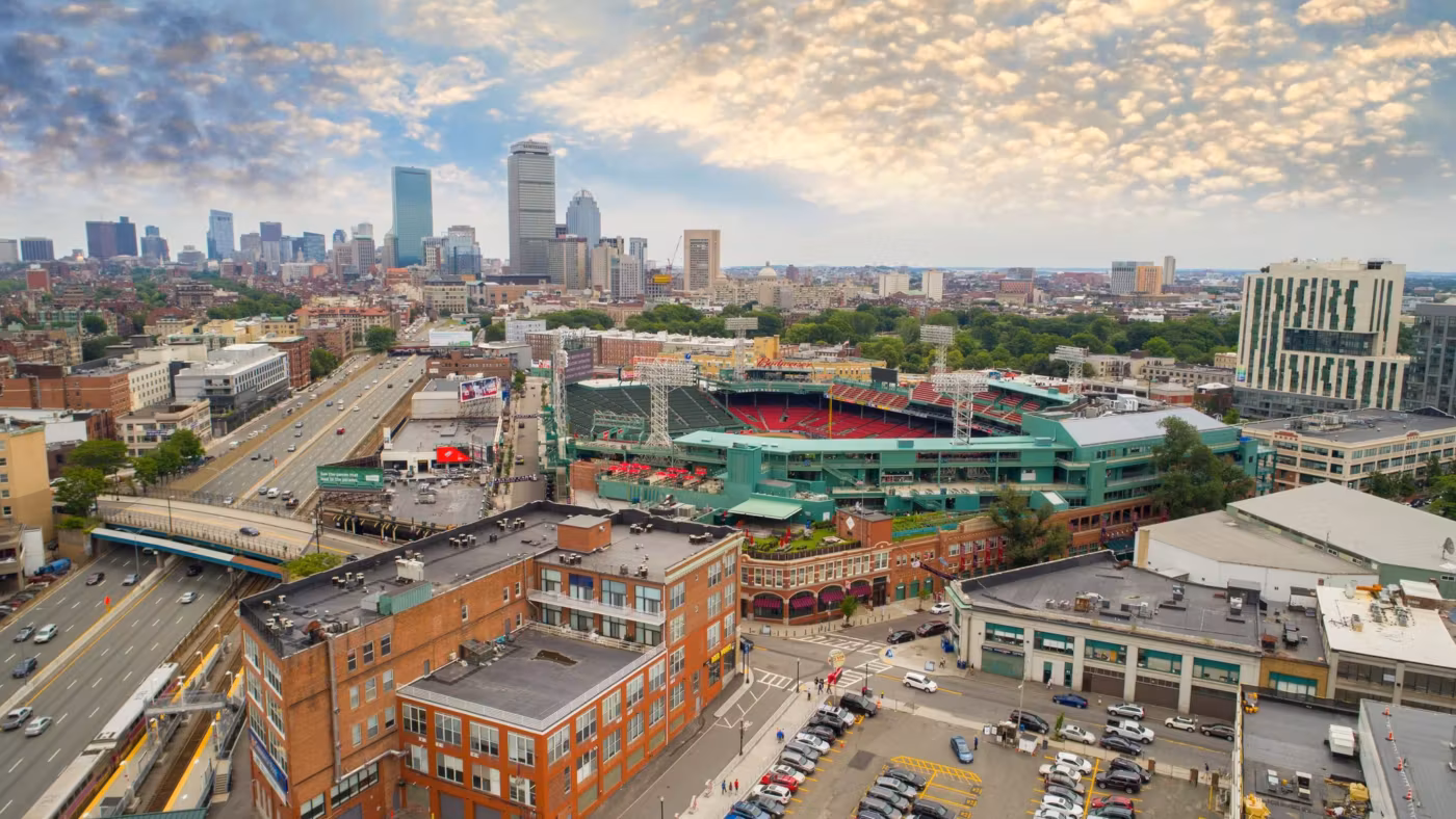 Boston rooftops and a ballpark from above with the skyline behind