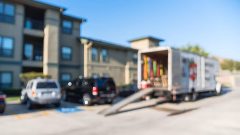 A moving truck with its ramp down outside an apartment building