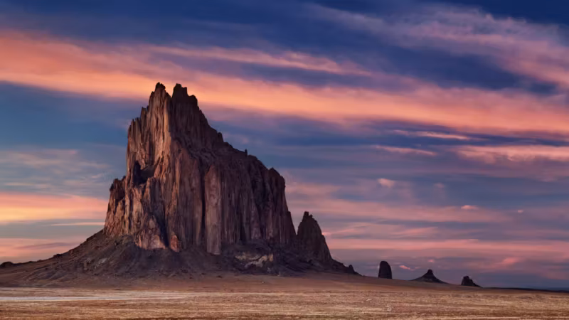 The Shiprock formation rising from the desert plain in New Mexico at sunset